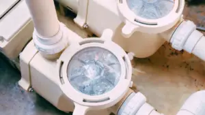 Pool pump strainer housings and plumbing on an equipment pad