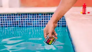 Hand dipping a pool water test kit into a swimming pool
